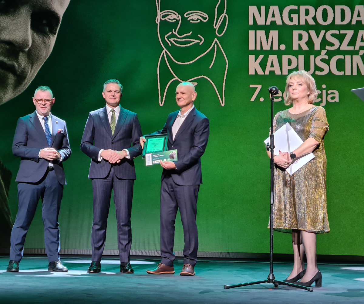 Ludzie na scenie pozujący do zdjęcia z nagrodą PAP im. Ryszarda Kapuścińskiego