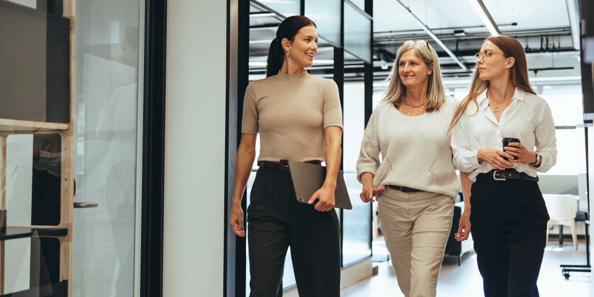 Trzy kobiety idące korytarzem w biurze