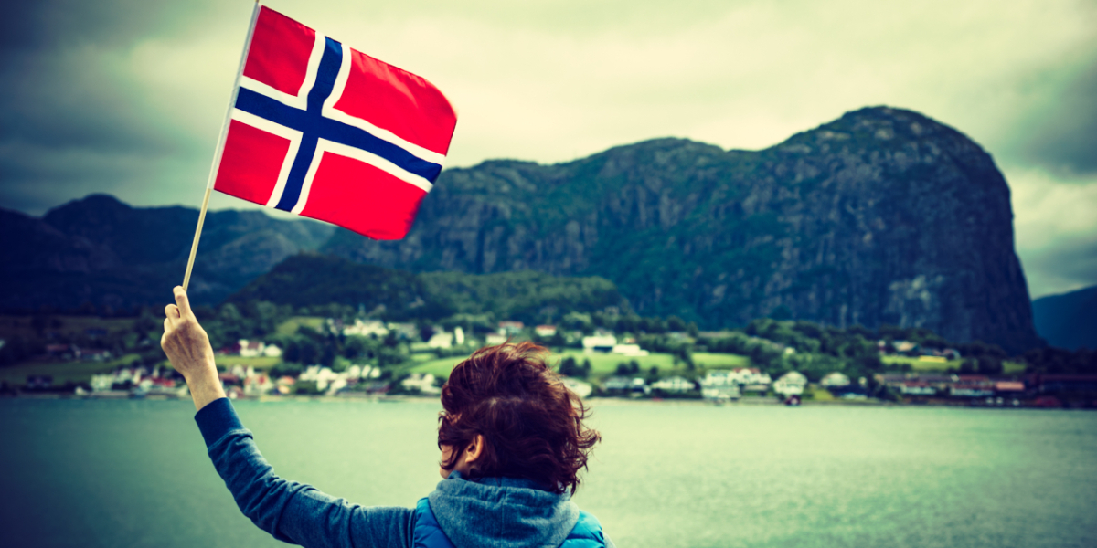 Kobieta trzymająca norweską flagę na tle fiordów