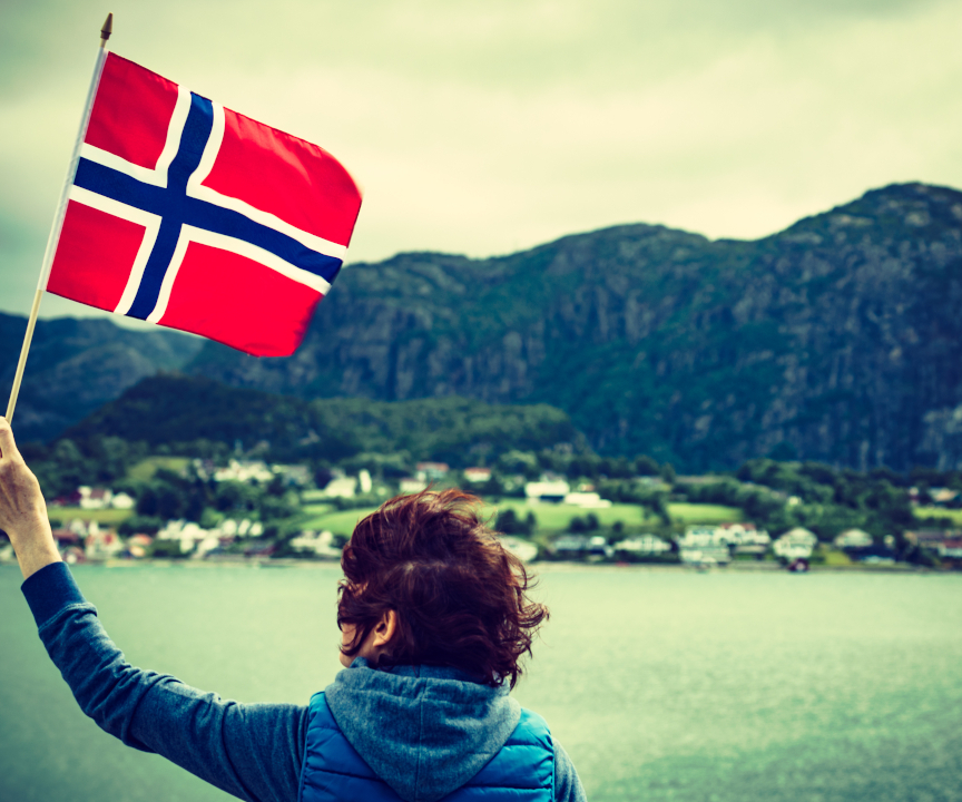Kobieta trzymająca norweską flagę na tle fiordów